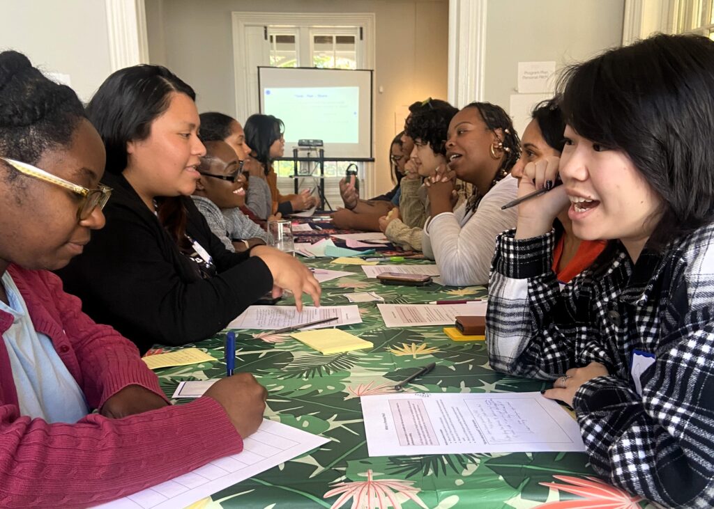 A group of people talk around a table indoors